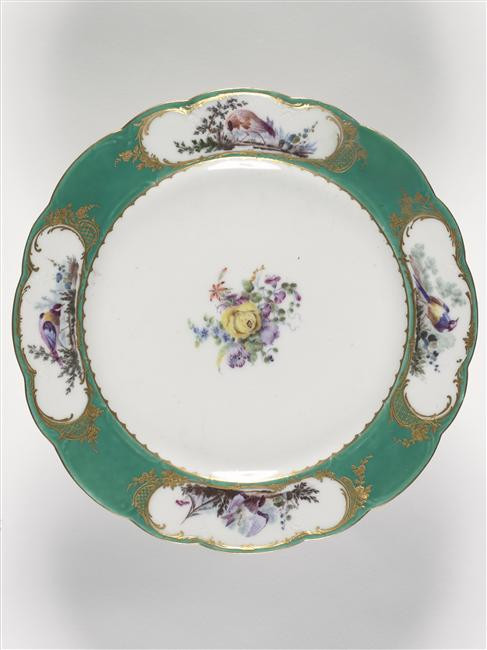 Photograph of a plate with a green border decorated with birds and flowers