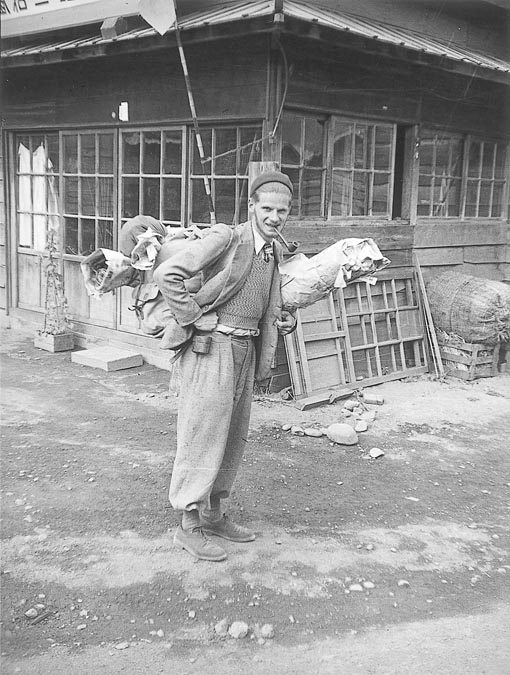 Black and white photograph of Leroi-Gourhan in Japan, carrying collected objects