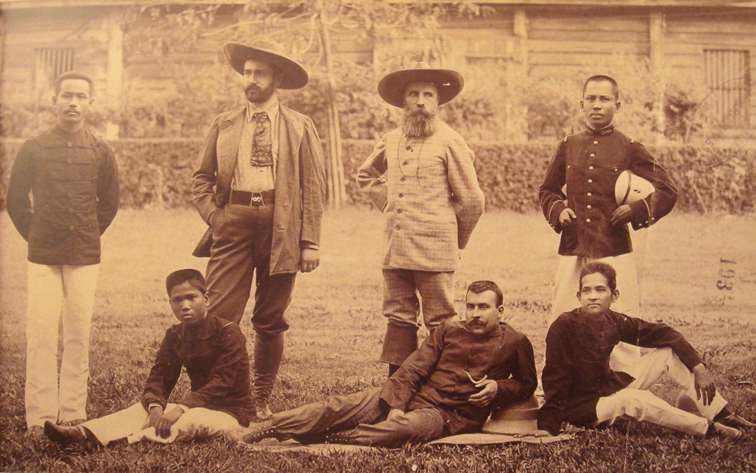 Photograph of seven men standing and sitting in the grass