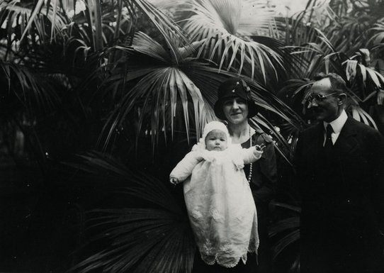 Photographie du couple portant un bébé asiatique habillé en blanc